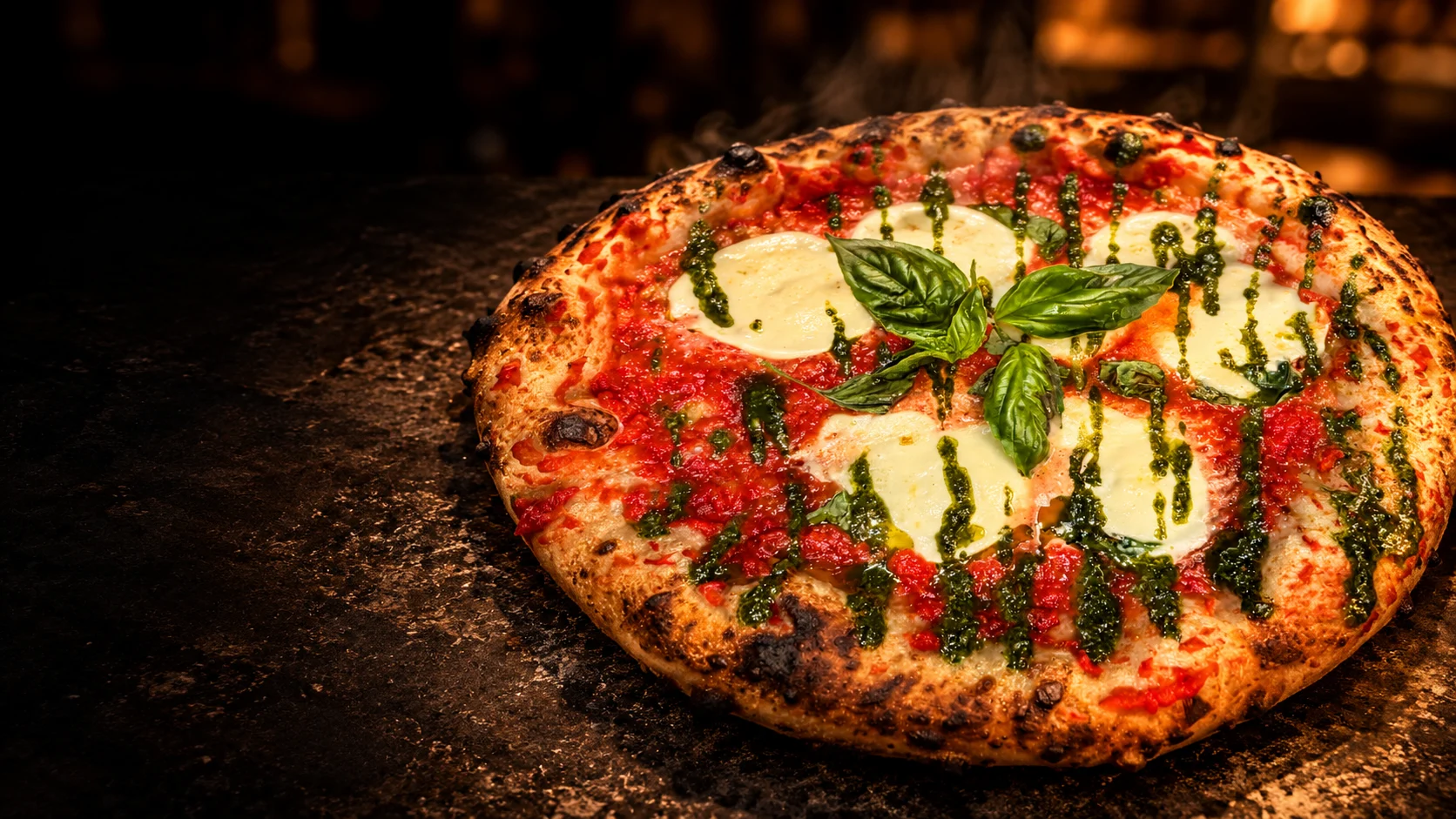 Pizza con pomodoro, bufala e basilico su un piano scuro